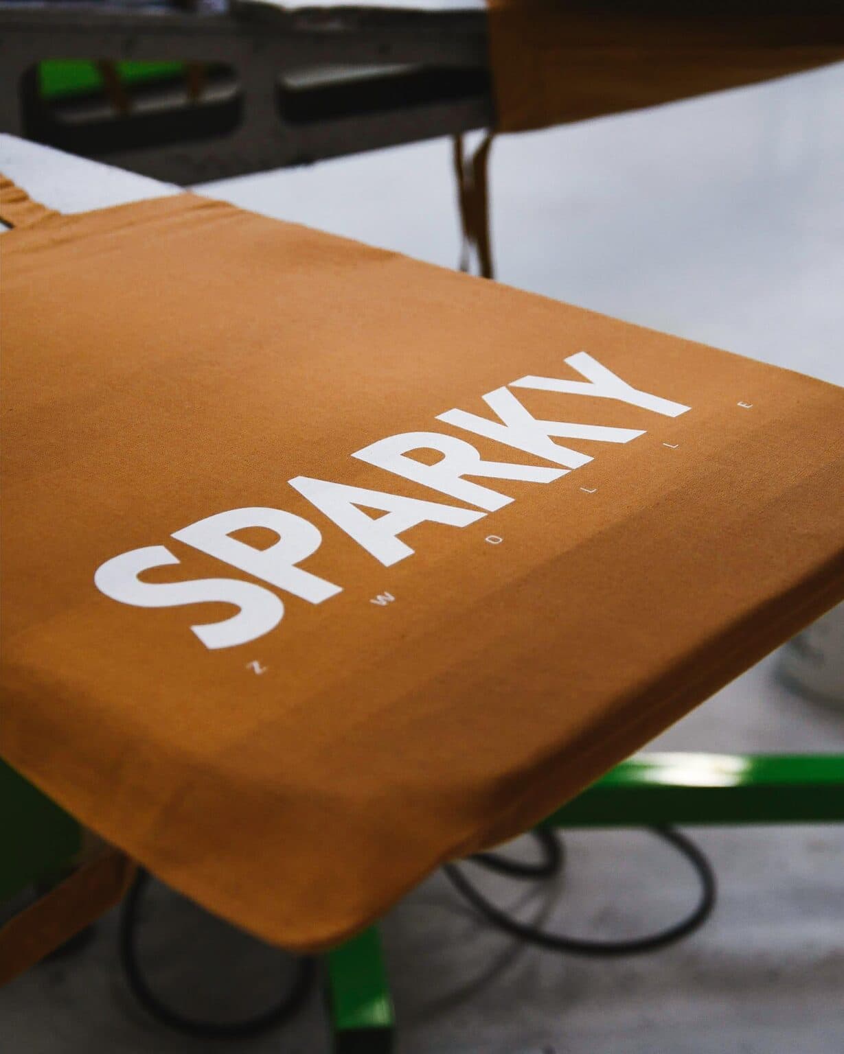 SPARKY printed on a tan garment on the press
